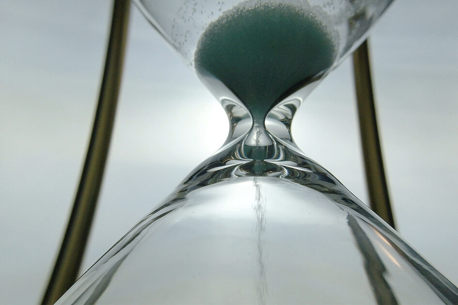 Extreme close up view of sand flowing through an hour glass. Super closeup of hourglass clock middle. Classic sandglass timer countdown.