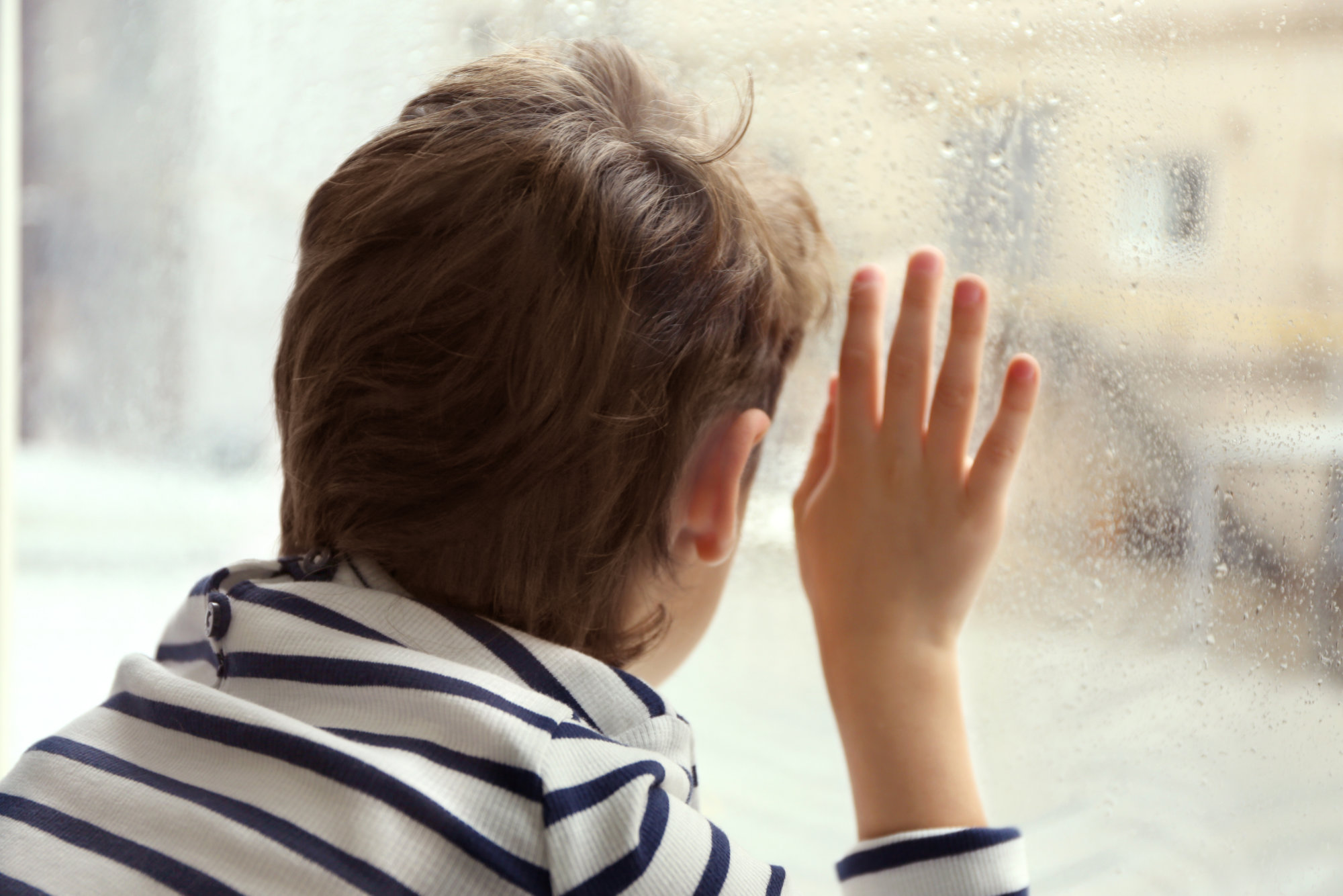 Close,Up,View,Of,Little,Boy,Looking,Out,Of,Window